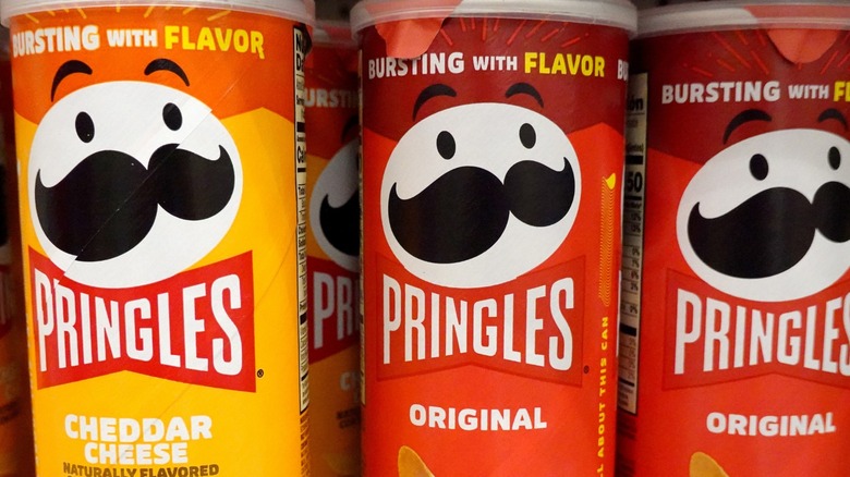 Close-up on three cans of Pringles on a supermarket shelf.