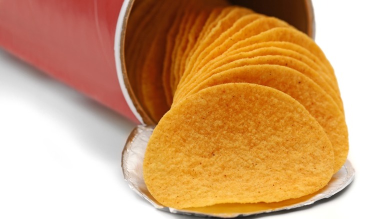 Close-up of Pringles-esque crisps pouring out of their can.