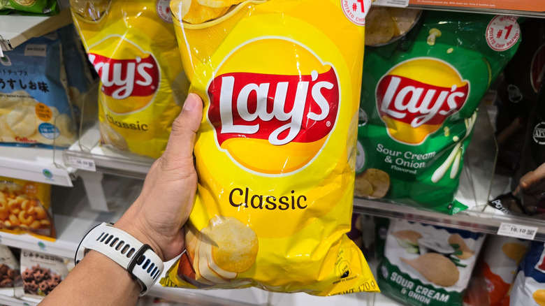 Hand holding bag of Lay's in store
