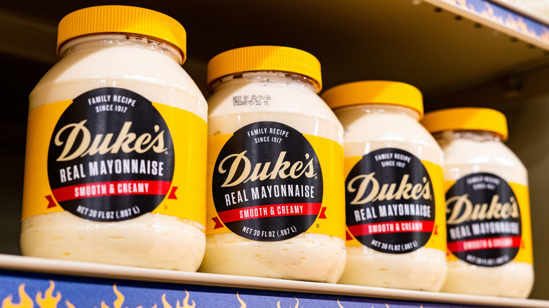 Several jars of Duke's mayonnaise on a store shelf.