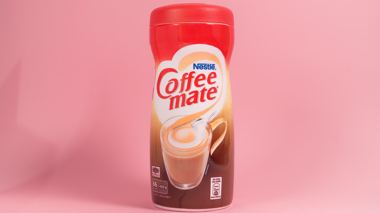 Container of Nestle Coffee mate powdered coffee creamer on pink background