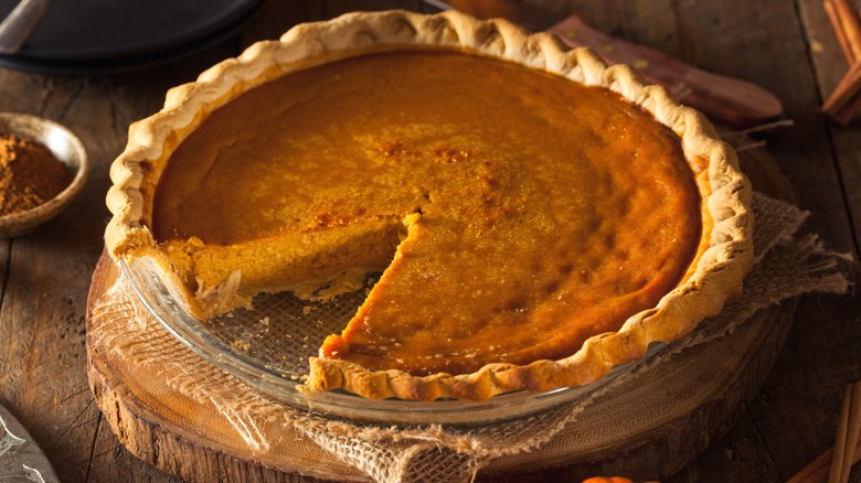 A pumpkin pie with a slice taken out of it.