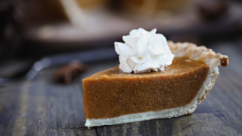 A slice of pumpkin pie with whipped cream.