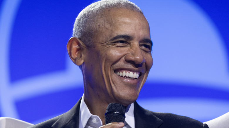 Barack Obama shown smiling while holding a microphone