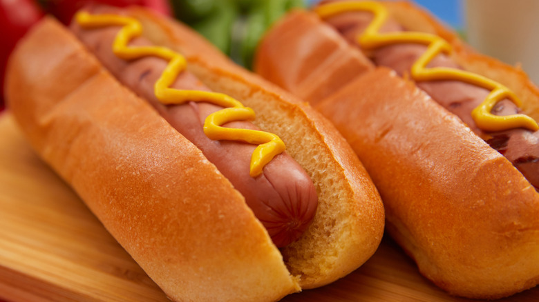 Two hot dogs in buns with mustard