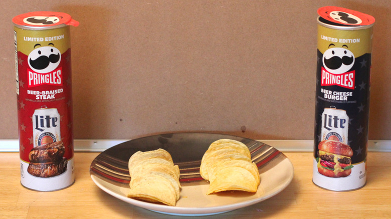 Two cans of limited edition Pringles x Miller Lite 2026 collaborative chips, beer-braised steak and beer cheese burger, in a red box