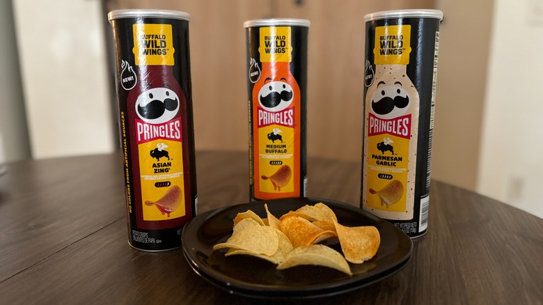 Pringles and Buffalo Wild Wings flavored crisps tubes and chips on plates on wooden table