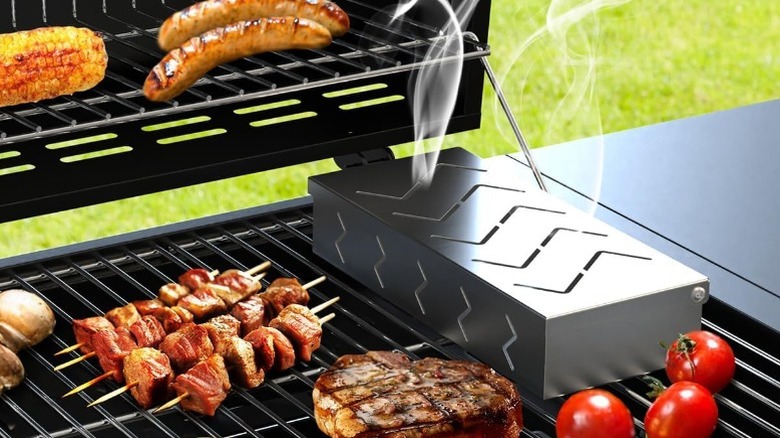 Smoker box on a propane grill with meat and vegetables