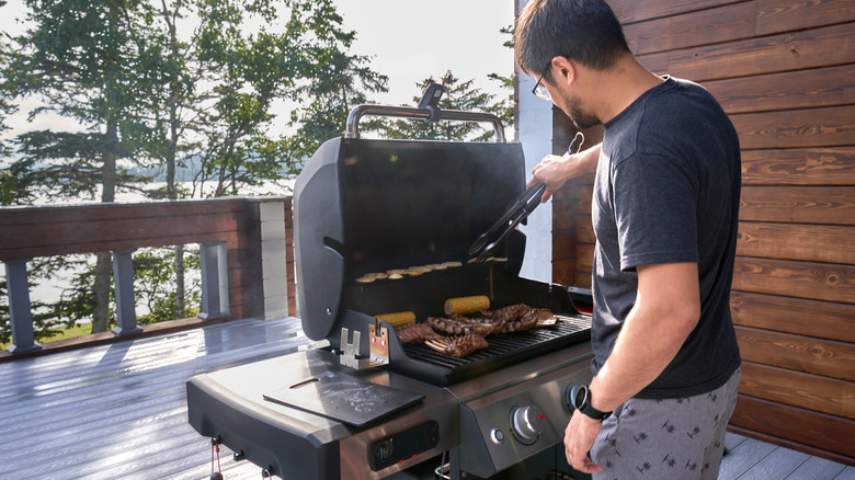 A young man grilling food on a balcony