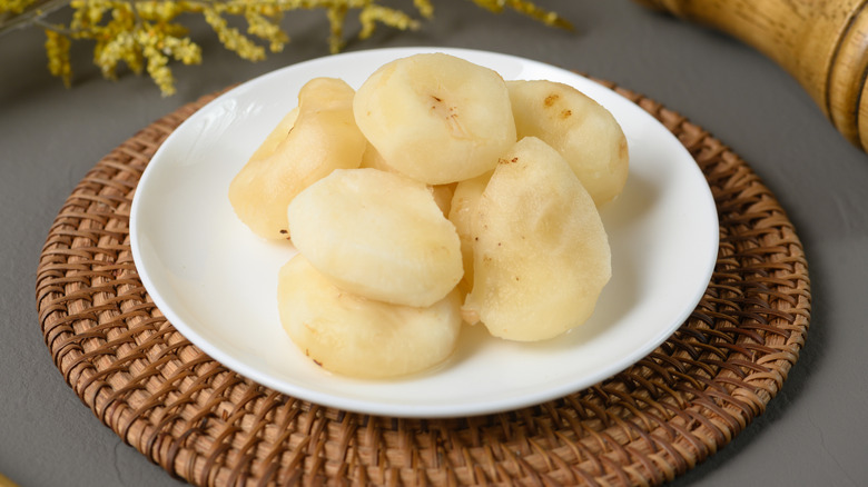 Plate of whole peeled water chestnuts on woven placemat