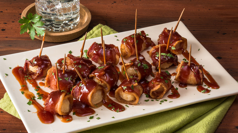 White platter with bacon-wrapped water chestnuts with brown sauce
