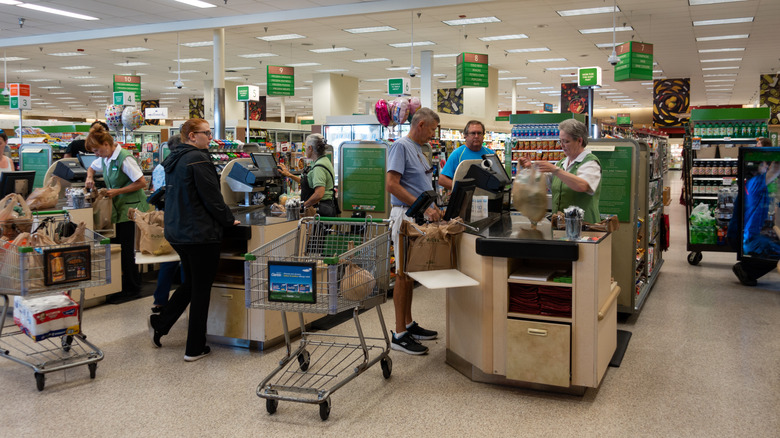 Cashiers serve shoppers at Publix checkout counters