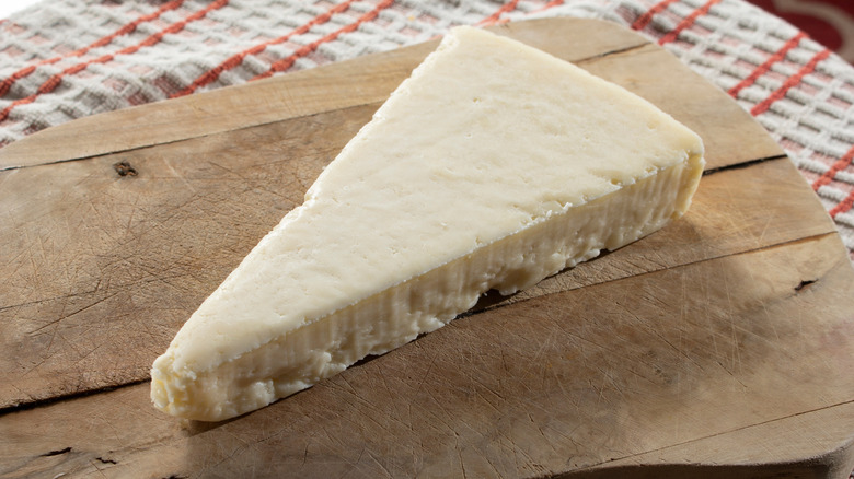 A wedge of cotija cheese on a cutting board.