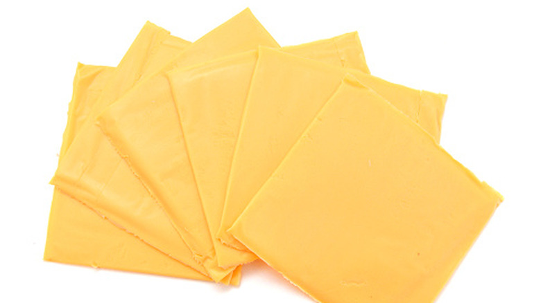 Six slices of processed American cheese fanned out on a white background.