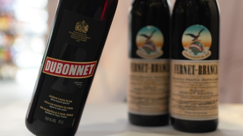 A bottle of Dubonnet, along with two other bottles of liquor.