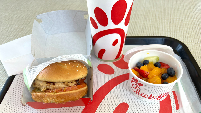 A Chick-fil-A meal on a tray with a grilled chicken sandwich, fresh fruit cup, and drink