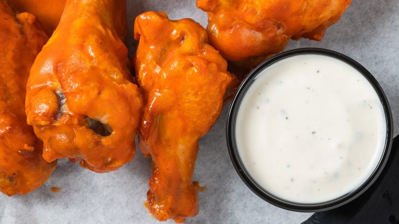A plate of Buffalo wings with a side of ranch for dipping