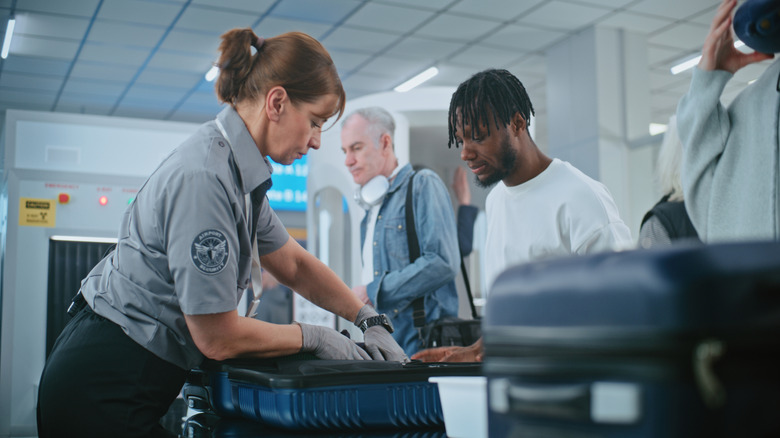 TSA officer searching through open carry-on bag at airport security screening