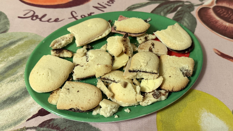 Pile of leftover Milano cookies with crumbs on a green plate