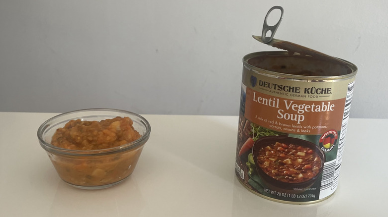 A bowl and can of lentil soup sit pon a counter