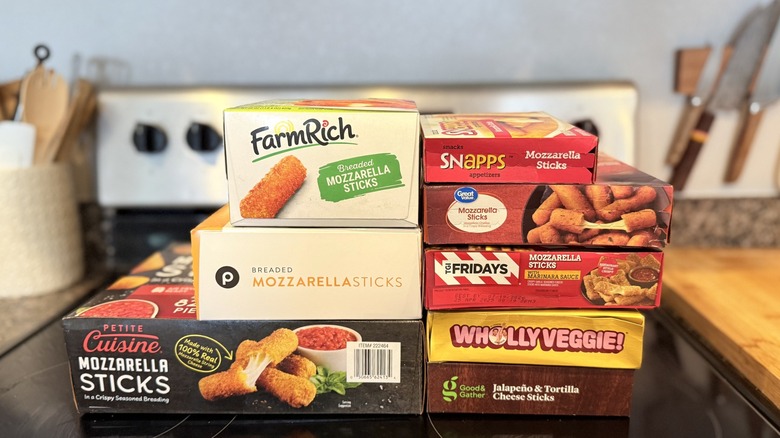 Boxes of frozen mozzarella sticks stacked on top of oven