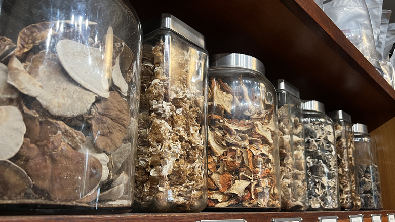 Glass jars filled with various dried mushrooms and vegetables