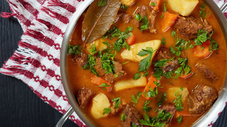 Top view of beef stew in pot potatoes, carrots, and parsley