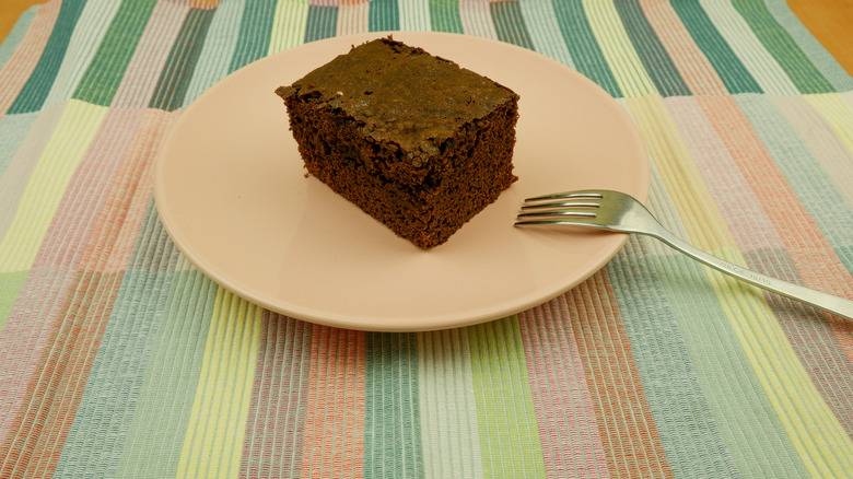 A slab of wacky cake on a pink plate with a fork.