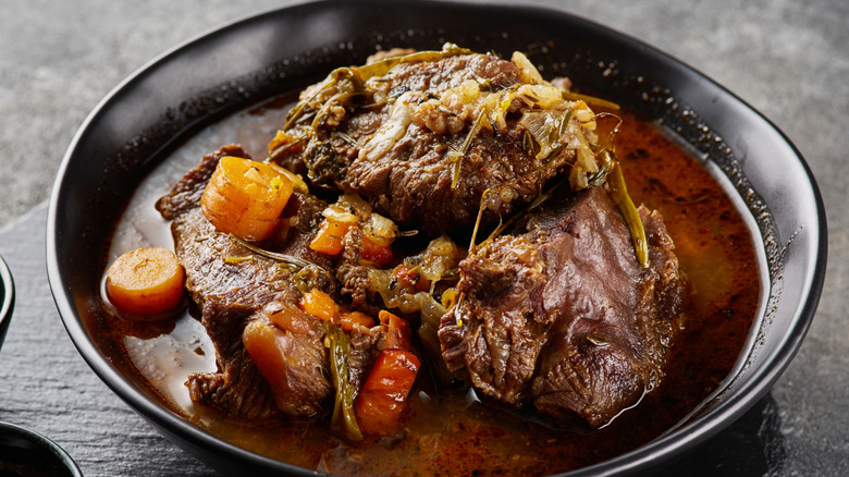 Braised beef with herbs and carrots in black bowl