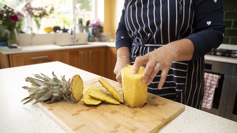 Woman cutting the peel off a pineapple