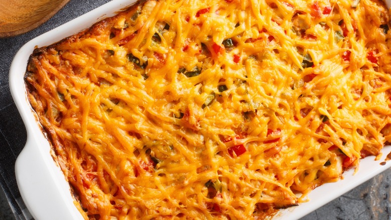 A casserole with shredded cheese and thin strips of tortilla chips on top of it.