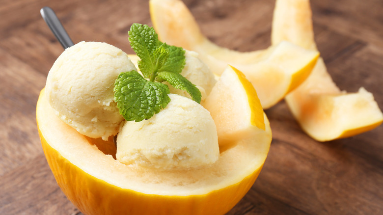 Scoops of ice cream in a light orange melon, topped with sprigs of mint