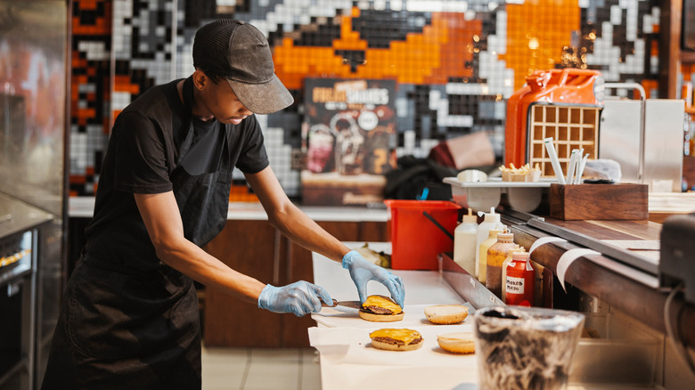 Employee fixing a cheeseburger in restaurant kitchen