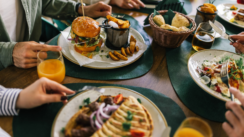 several meals are shown on a table including a burger, salad and chicken dish