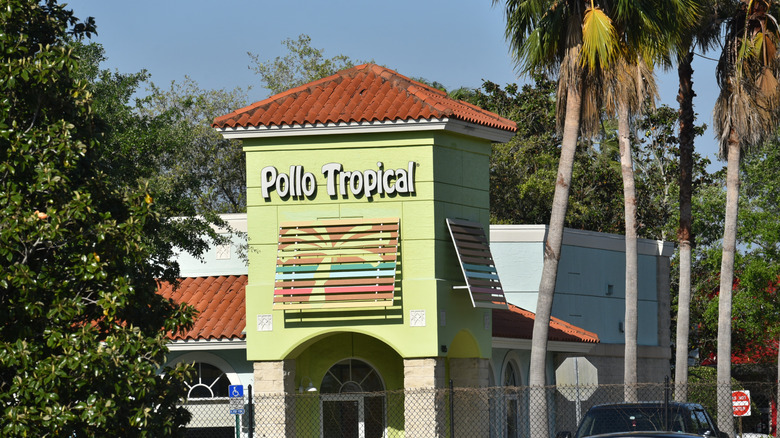 exterior of a Pollo Tropical restaurant with palm trees