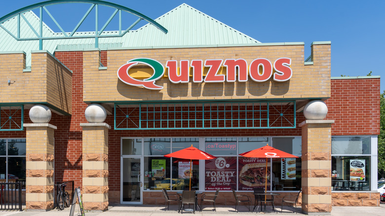 A red brick Quiznos restaurant is shown in Oakville, Ontario, Canada with outside tables with shade umbrellas