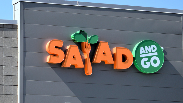 A Salad and Go restaurant sign, with a fork loaded with lettuce in the place of the L in "salad"