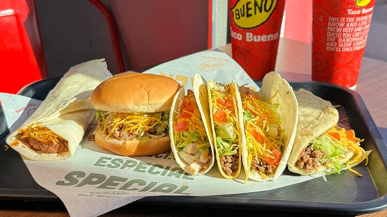 Four tacos on tray with burger and burrito