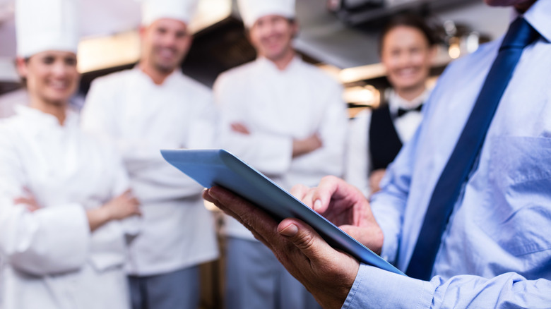Mid section of restaurant manager using digital tablet in commercial kitchen