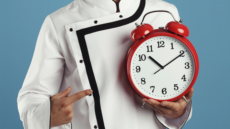 Chef holding a red alarm clock