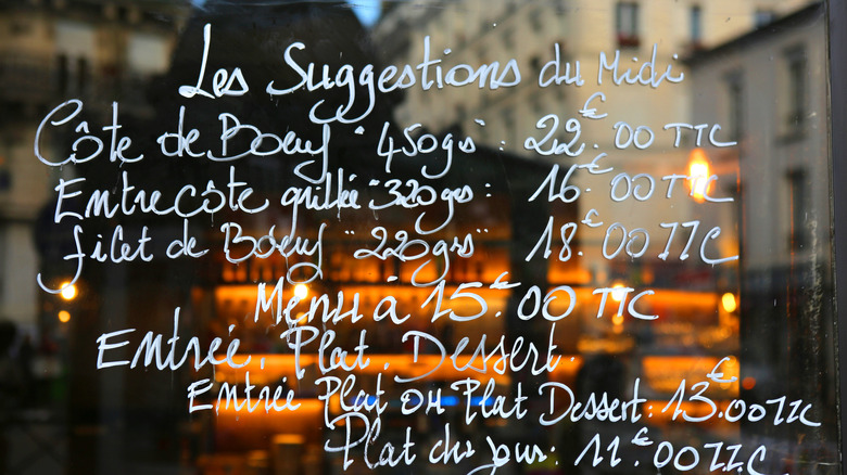 Menu with prices written on a bistro window in France