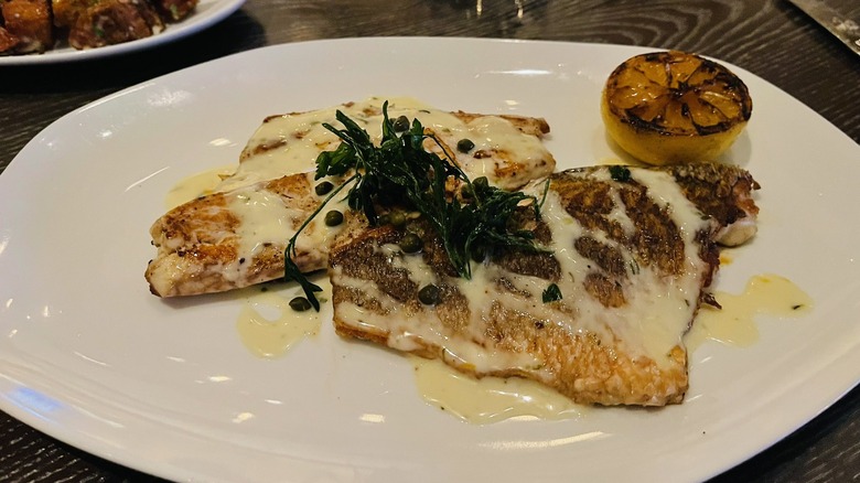 Grilled red snapper with lemon and capers on plate