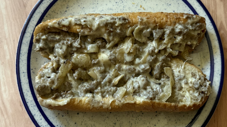 Arby's Angus Cheesesteak open on plate to show gooey meat, veggie, and cheese innards