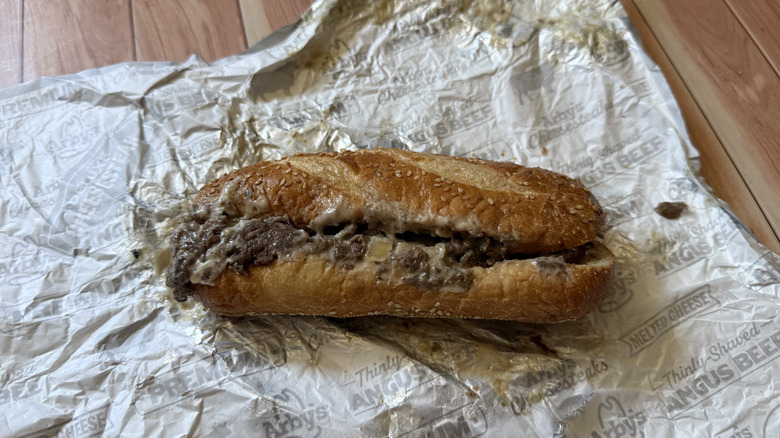 Arby's Angus Cheesesteak sandwich sits on foil wrapper