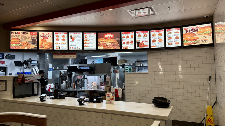 Menu at Arby's behind empty counter inside restaurant with view of kitchen