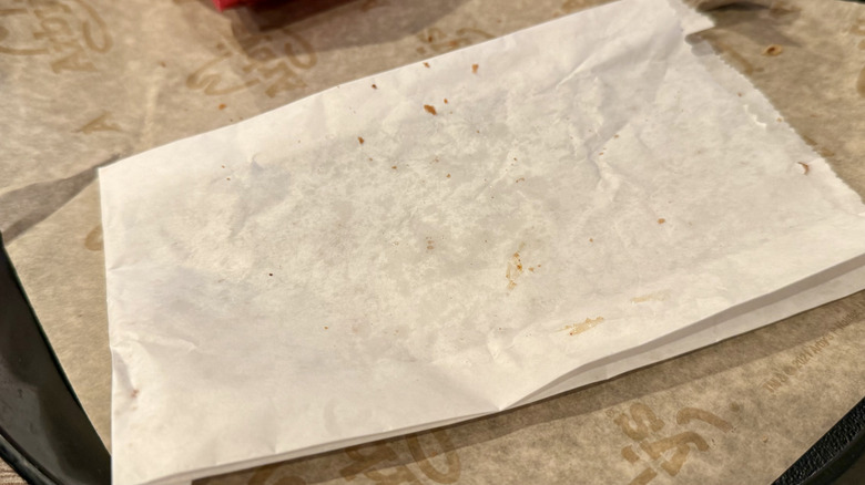 Peach cobbler roll crumbs scattered on paper bag on Arby's tray