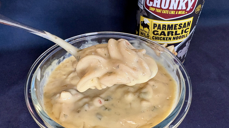 Spoonful of soup over bowl of Campbell's Chunky Buffalo Wild Wings Parmesan Garlic Chicken Noodle Soup