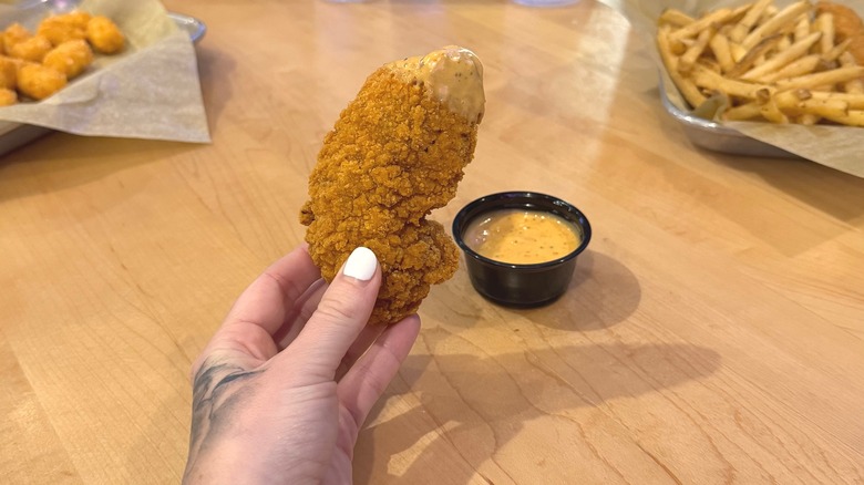 Person holding chicken dipper with sauce