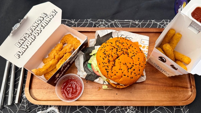 Burger, nuggets, mozzarella sticks and ketchup on wooden board