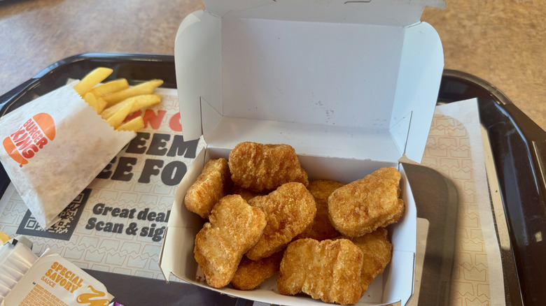 A tray with an open container of nuggets and a small fry.